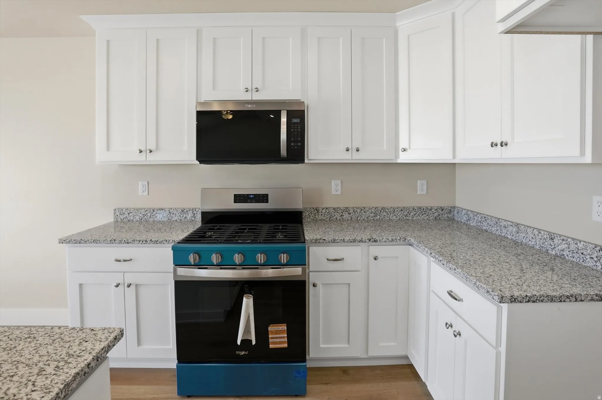 White shaker cabinetry with crown molding, granite countertops, and stainless steel appliances