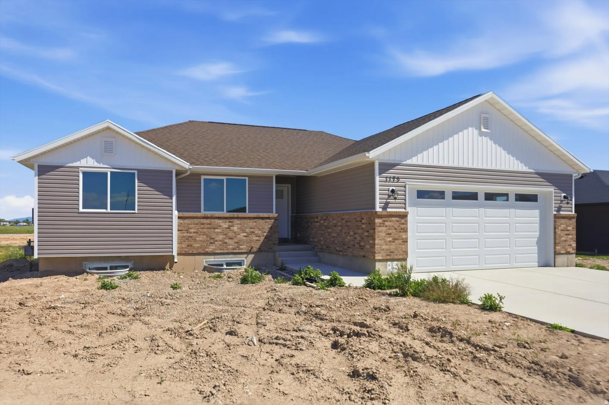 Contemporary exterior featuring horizontal siding, brick accents, white trim, a brown shingle roof, and an attached two-car garage with a concrete driveway