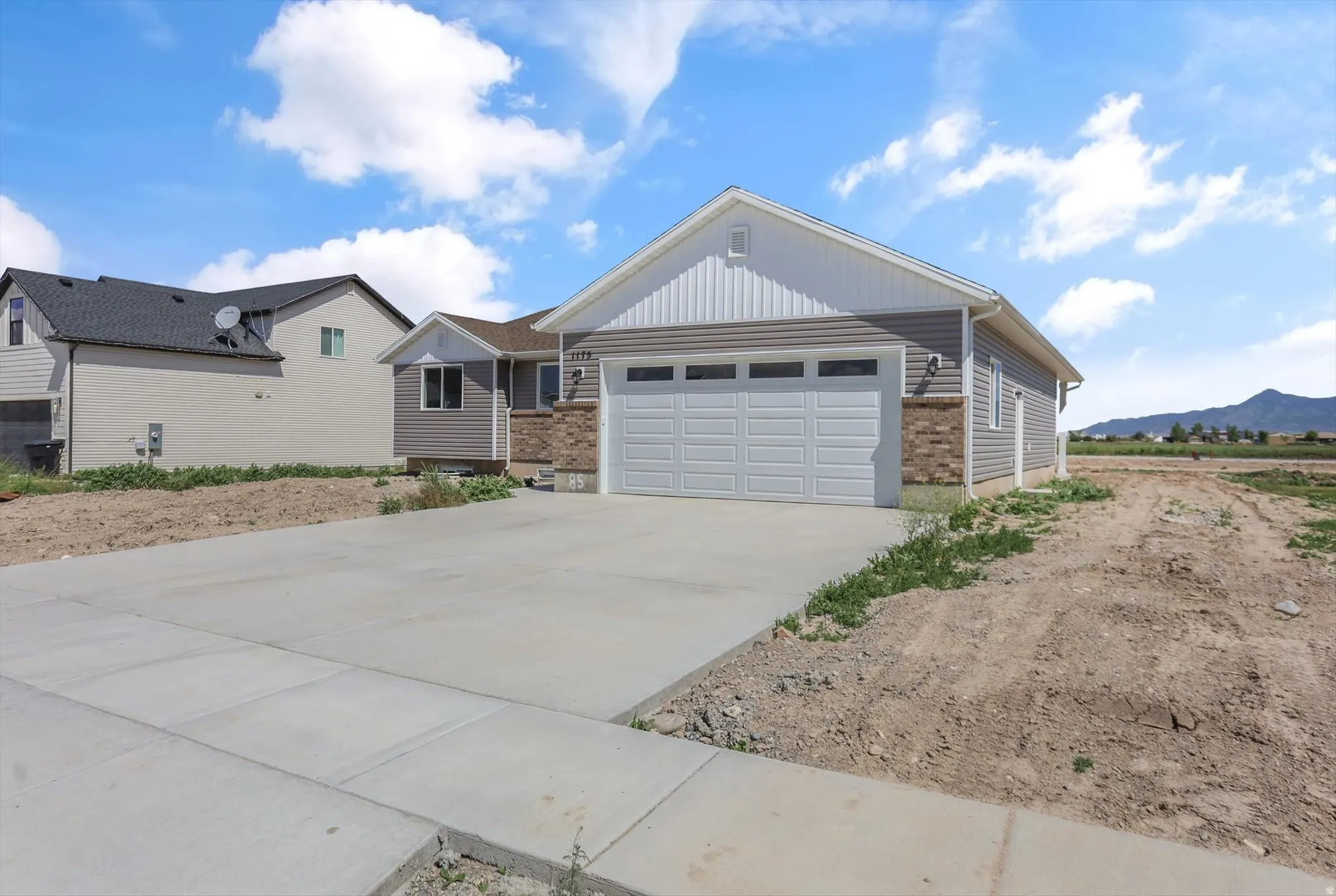 Newly constructed residence featuring a two-car garage, concrete driveway, and a combination of horizontal siding and brick accents