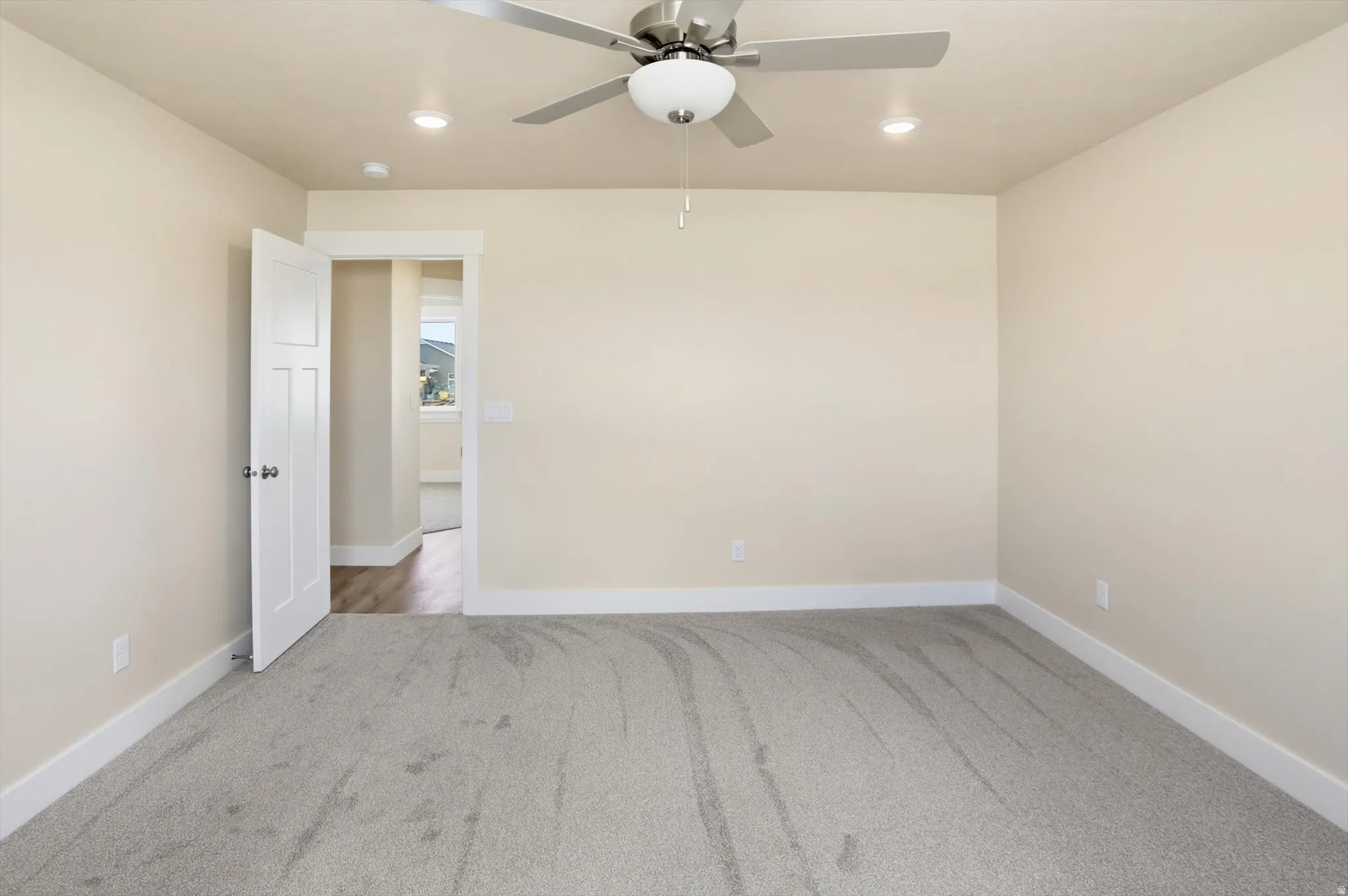 Neutral-toned interior room featuring light gray carpeting and white baseboards