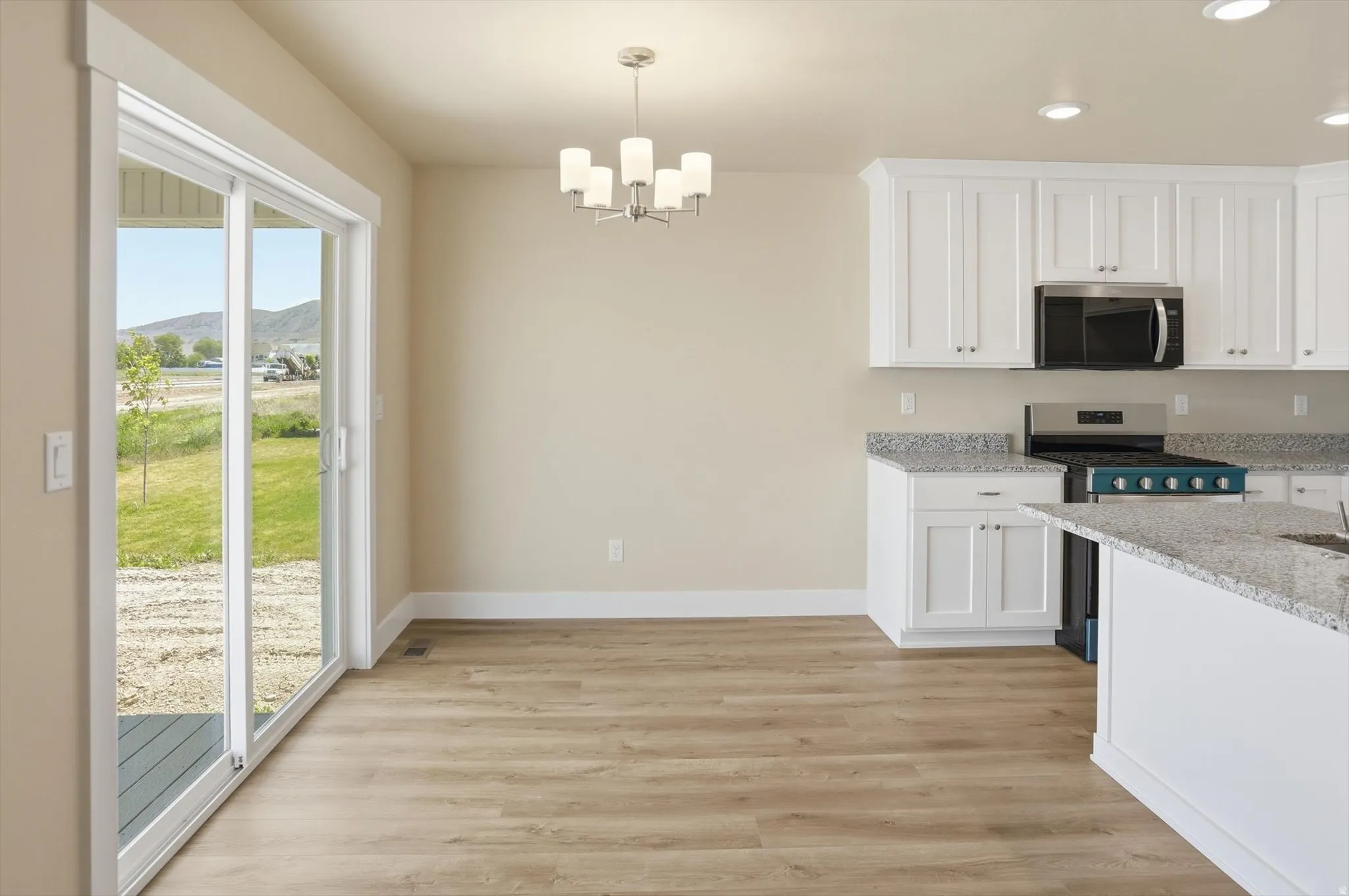 Open-concept dining area featuring wood-finish flooring, a contemporary chandelier, and a sliding glass door