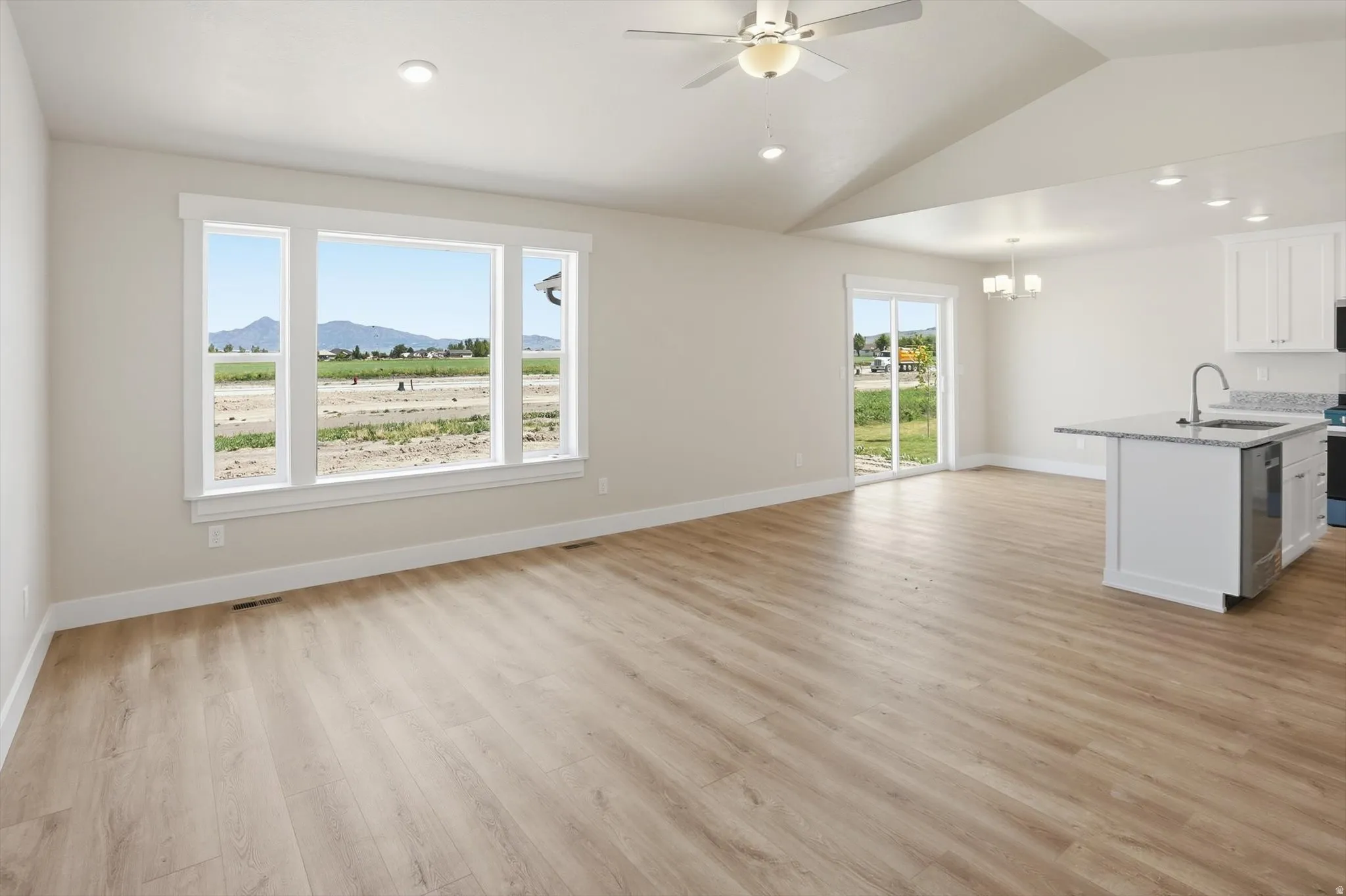 Open-concept living space featuring wood-finish flooring, vaulted ceilings, and recessed lighting