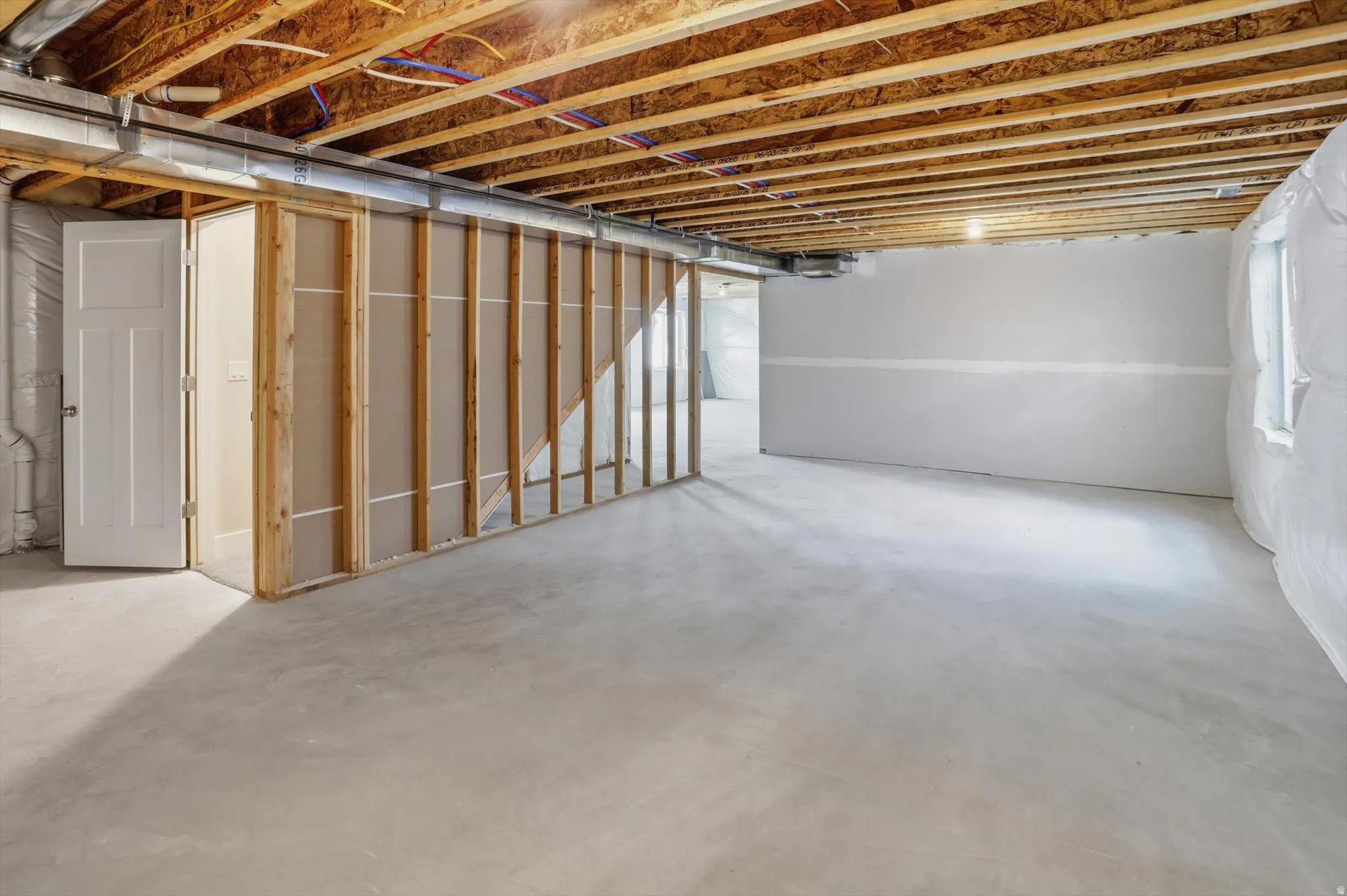 Unfinished basement with exposed wood ceiling joists and concrete flooring