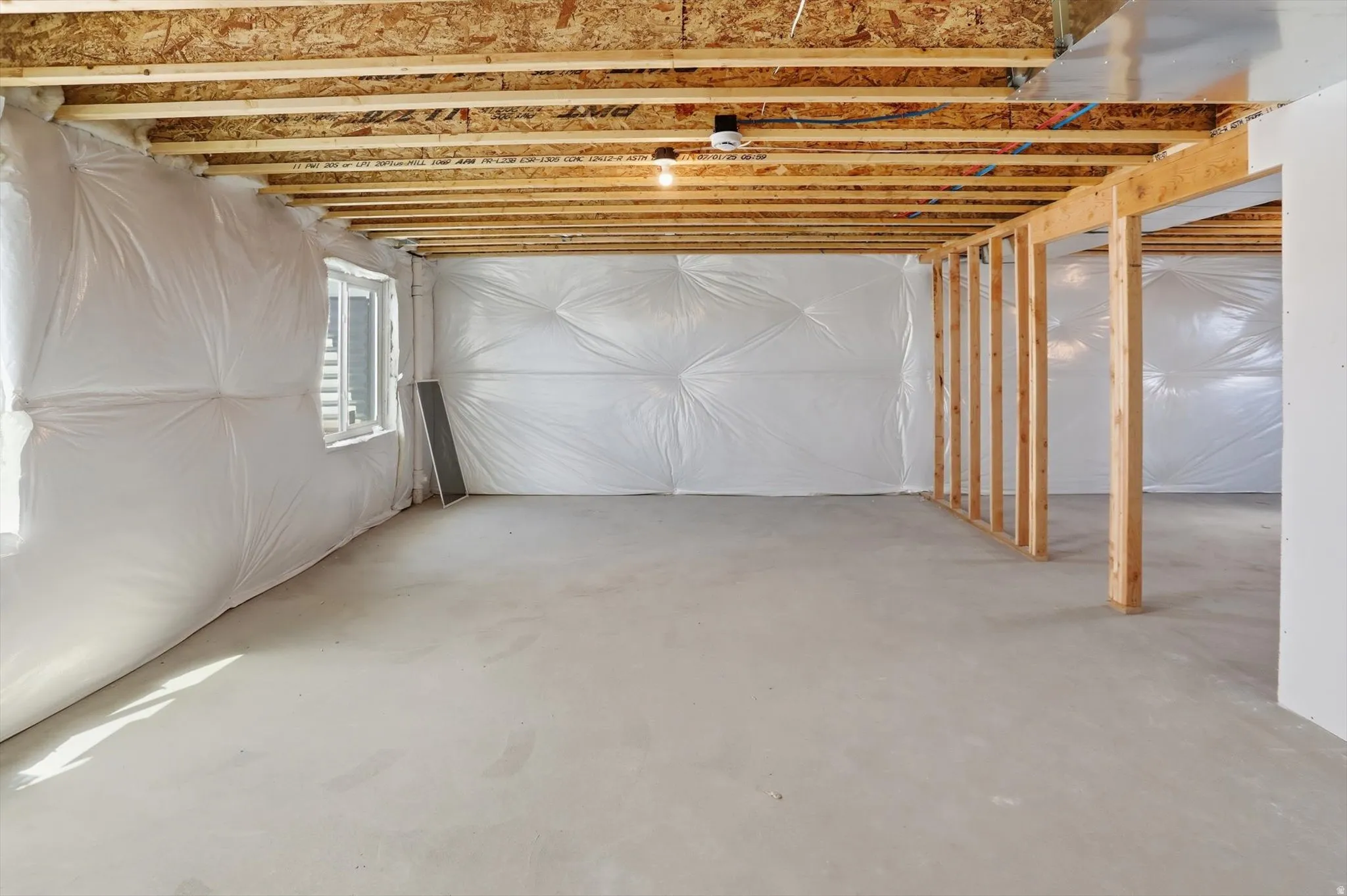 Spacious unfinished lower level featuring exposed wood ceiling joists and a concrete floor