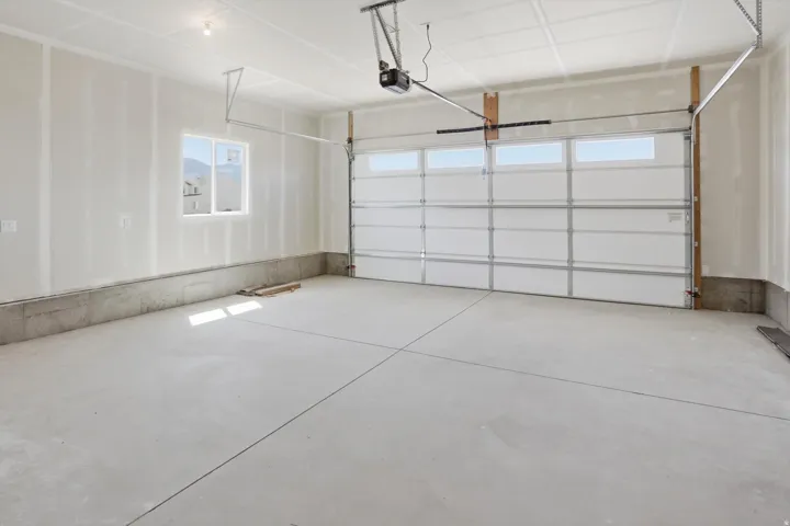 Spacious garage featuring a concrete floor, an overhead garage door with integrated windows, and a single window providing natural light