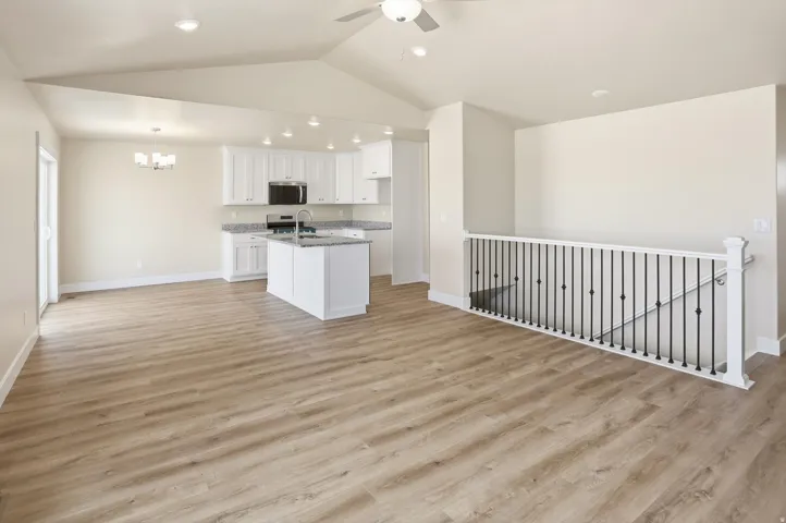 Spacious living area featuring wood-finish flooring, a vaulted ceiling, and recessed lighting