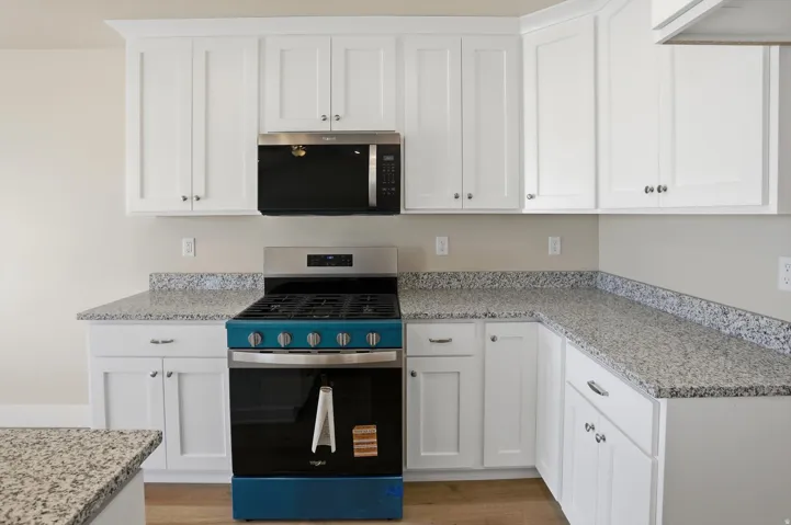 White shaker cabinetry with crown molding, granite countertops, and stainless steel appliances