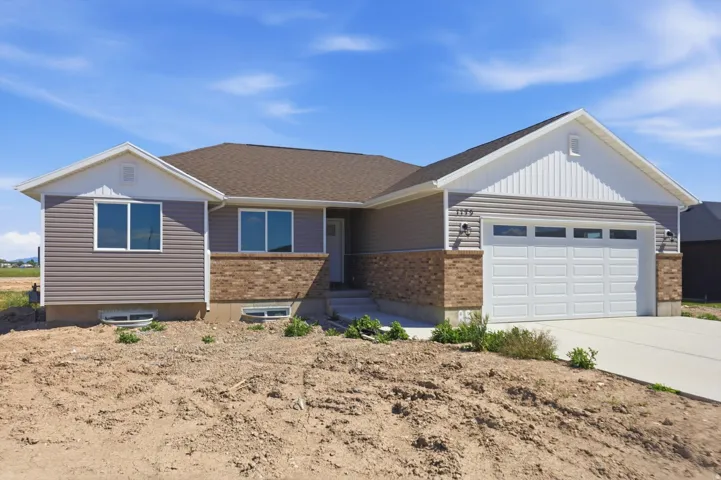 Contemporary exterior featuring horizontal siding, brick accents, white trim, a brown shingle roof, and an attached two-car garage with a concrete driveway