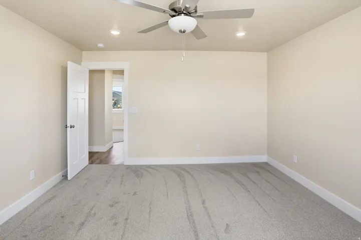 Neutral-toned interior room featuring light gray carpeting and white baseboards