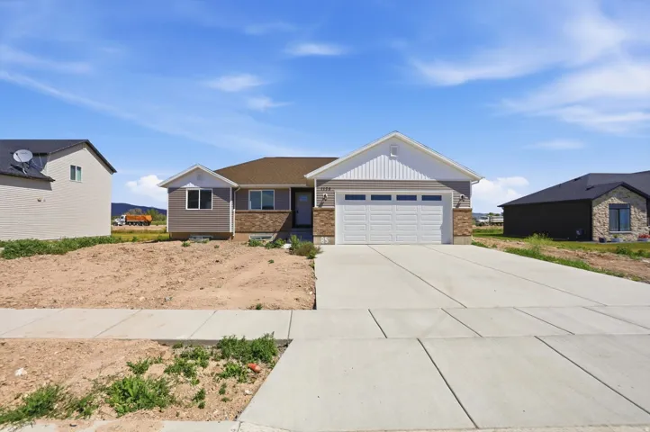 Single-story residence featuring a two-car garage, partial stone facade, and siding