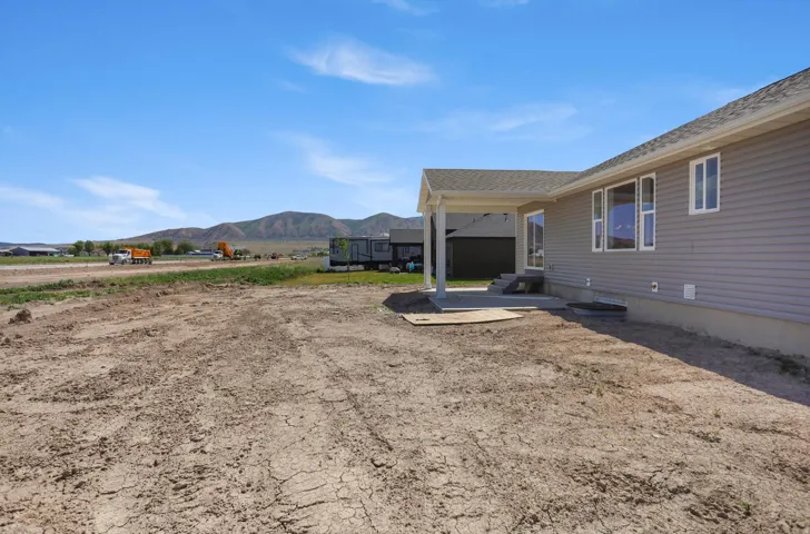 Rear exterior featuring a covered patio, multiple windows, and a bare ground yard