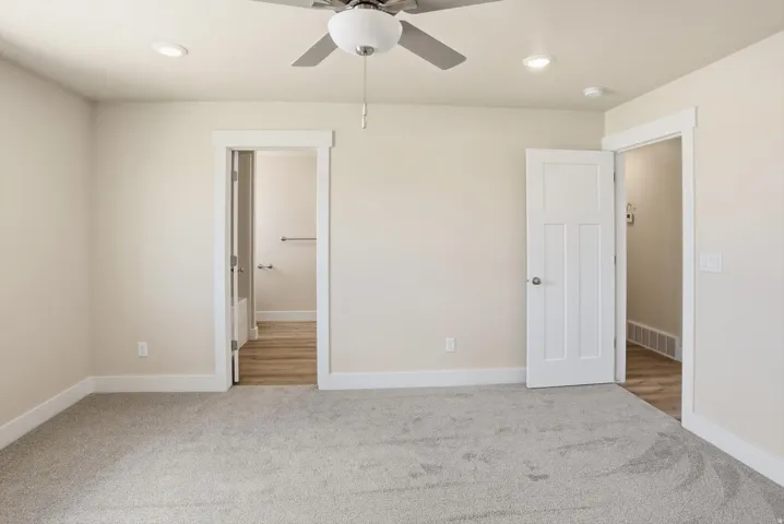 Spacious room featuring neutral carpeting, recessed lighting, a ceiling fan, and white trim throughout
