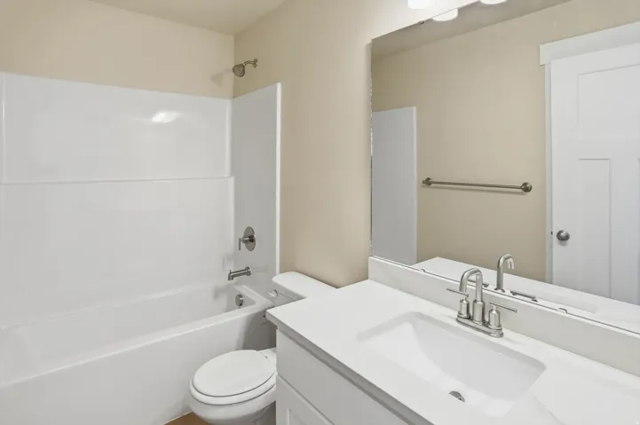 Bathroom featuring a white vanity with an integrated sink, brushed nickel faucet, and a large mirror