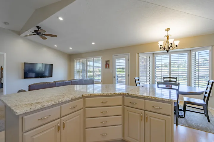 Kitchen island with a granite countertop and ample cabinetry, overlooking a dining area with a chandelier