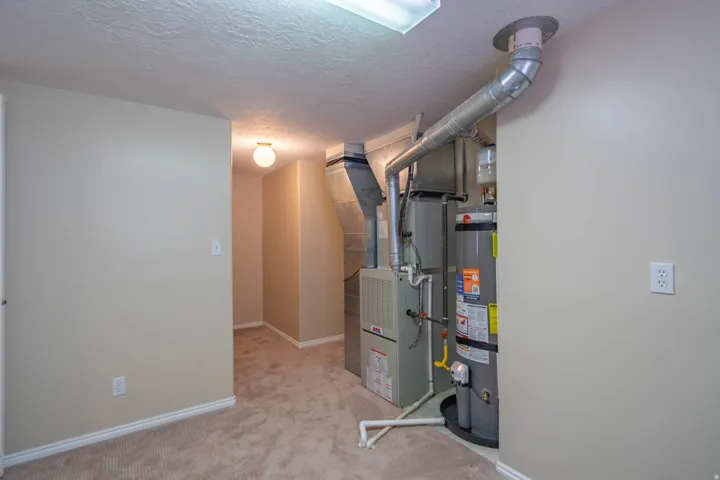 Utility space featuring a water heater, furnace, and exposed ductwork (storage around corner)