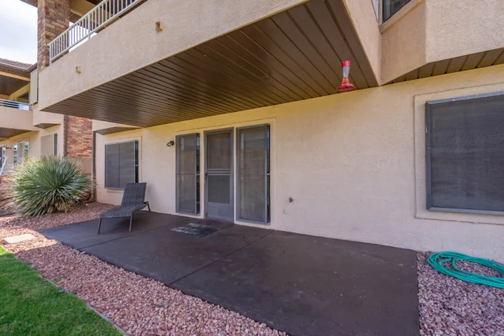 Ground-level patio featuring stucco exterior, brick architectural accents, and screen-enclosed sliding glass doors