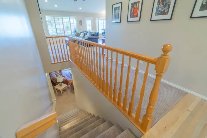 Multi-level interior featuring wood-finish railings and balusters, carpeted stairs, and light-toned wall finishes