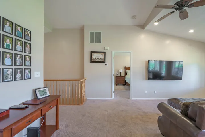 Carpeted landing with vaulted ceiling, recessed lighting, and a ceiling fan, with entry to primary bedroom