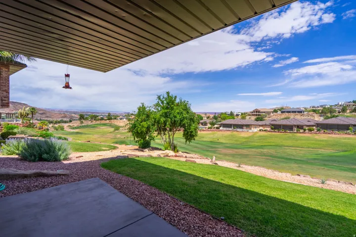 View from the covered patio with concrete surface, gravel landscaping, and maintained lawn areas