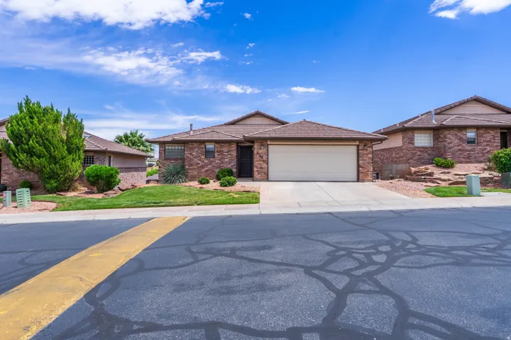 Single-story residence featuring a two-car garage, brick facade, and a tiled roof