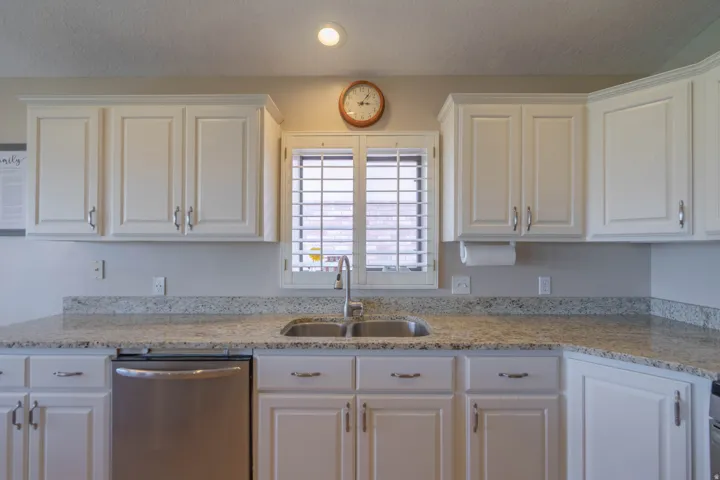 Kitchen with white cabinetry, stainless steel sink, and light-toned countertops