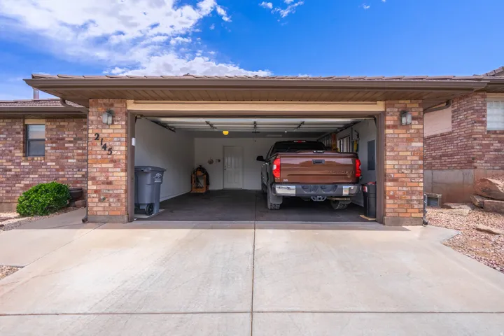 Attached two-car garage with a concrete driveway, brick exterior, and tile roof
