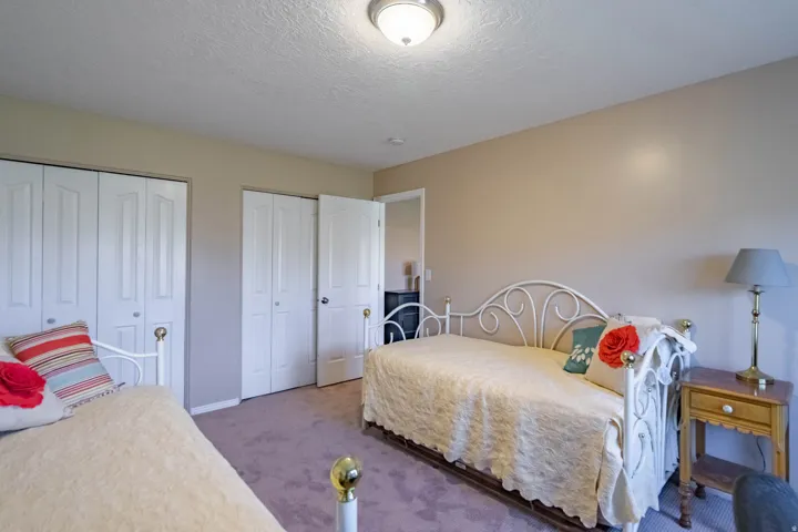 Carpeted downstairs 2nd bedroom featuring two sets of bi-fold closet doors and a standard interior door