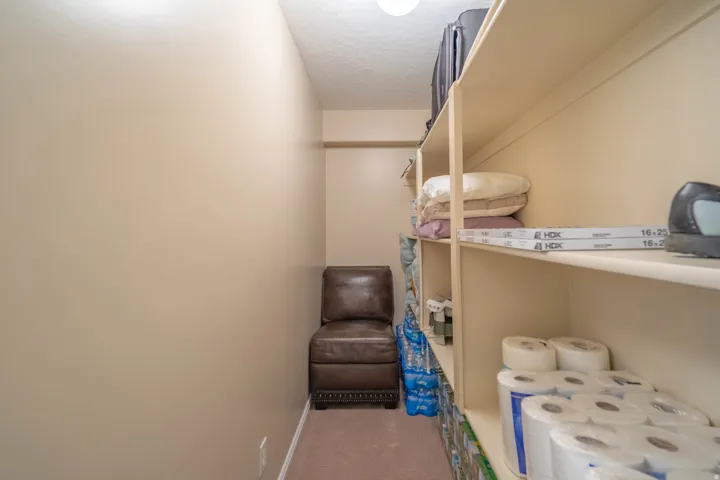 Dedicated storage space featuring extensive built-in shelving, neutral wall tones, and recessed lighting