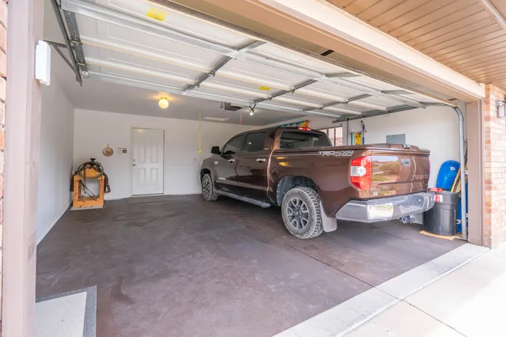 Two-car garage featuring a direct entry door, overhead lighting, and a durable floor finish.  Fits a truck!