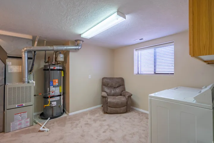 Utility space featuring a water heater, furnace, and a window with blinds