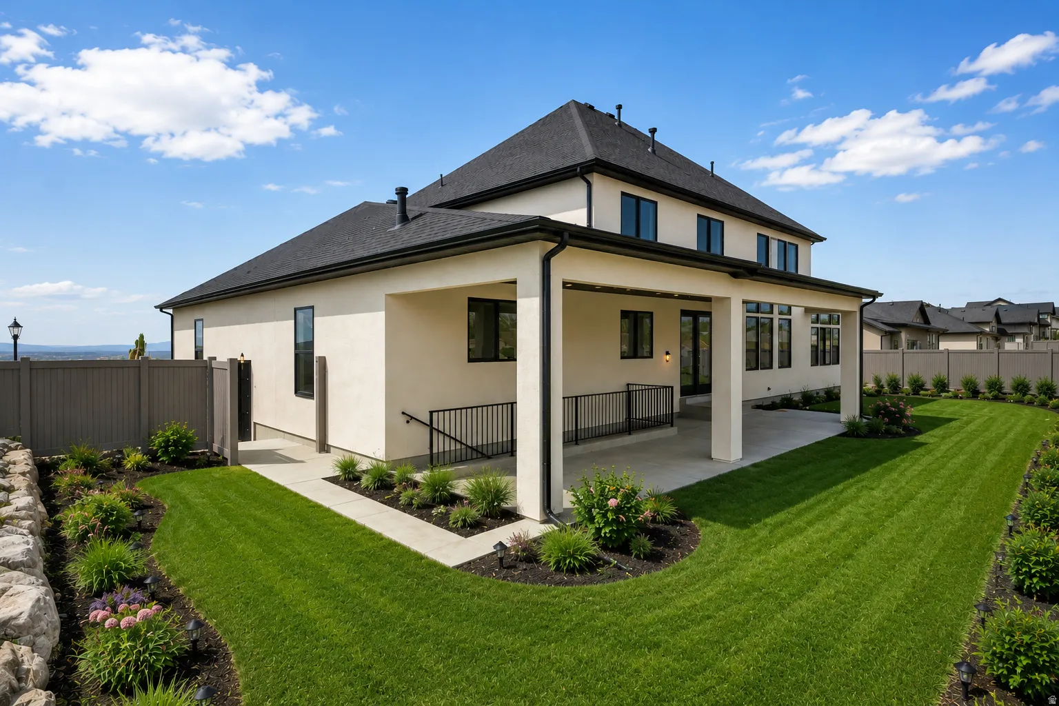 Spacious rear exterior featuring a covered patio, with staged landscaping.