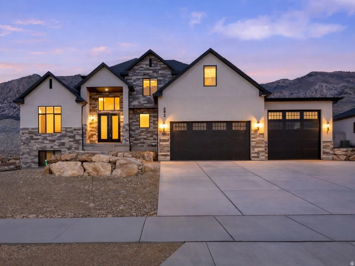 Modern architectural residence featuring a stone and stucco exterior, prominent entryway, and multiple gabled rooflines