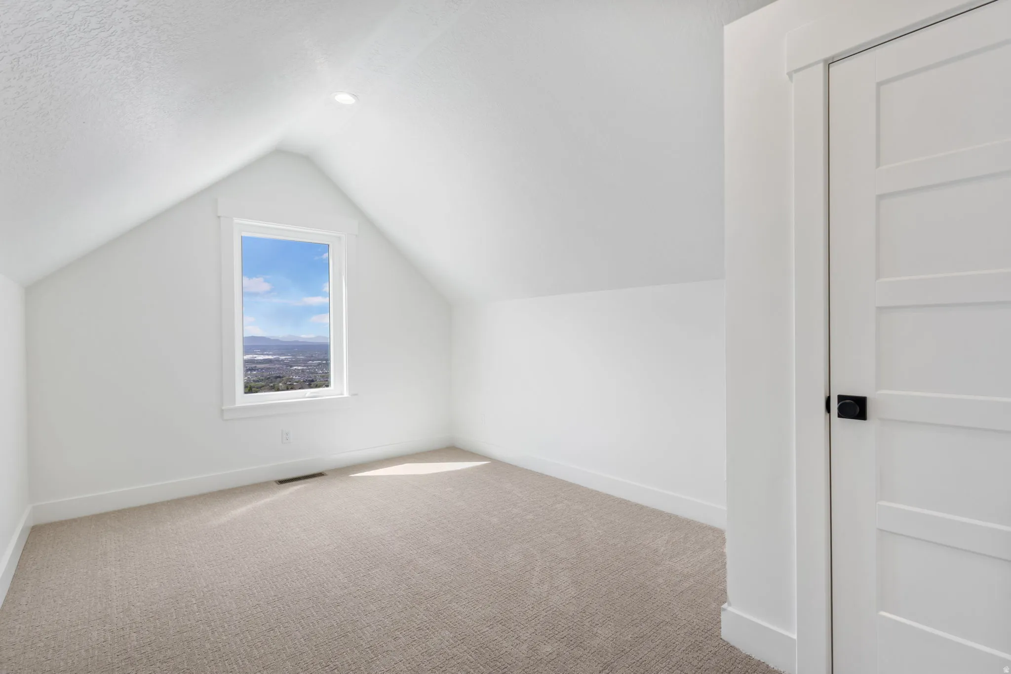 Attic room featuring a single-pane window with white trim, a recessed ceiling light, and a light-colored carpeted floor