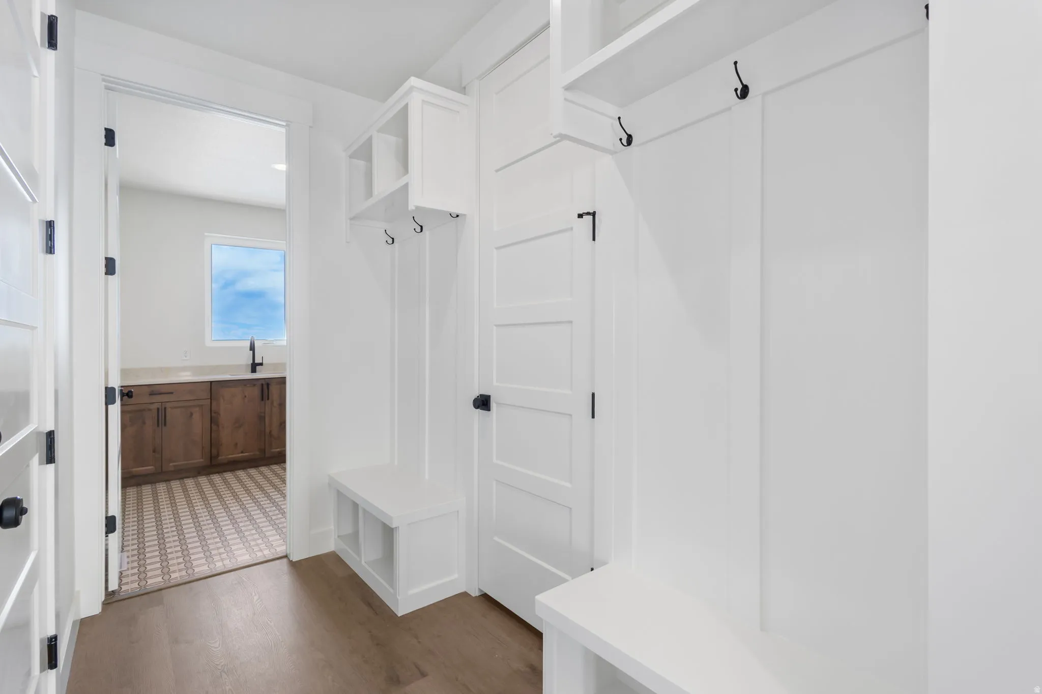 Entryway mudroom with built-in bench storage, integrated shelving, and coat hooks