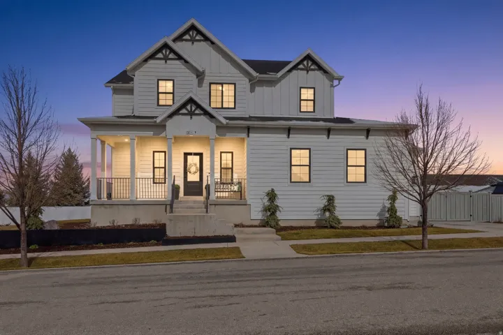 Two-story white exterior with board and batten gables, black-trimmed windows, a covered front porch with white columns, and concrete steps with black railings