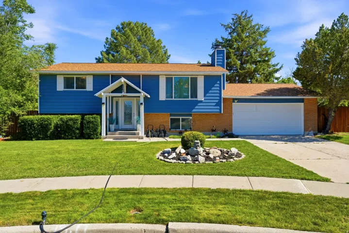 Split-level residence featuring a vibrant blue siding, brick accents, and a brown shingle roof