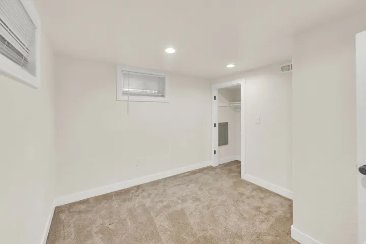 Carpeted room with recessed lighting and two windows featuring blinds