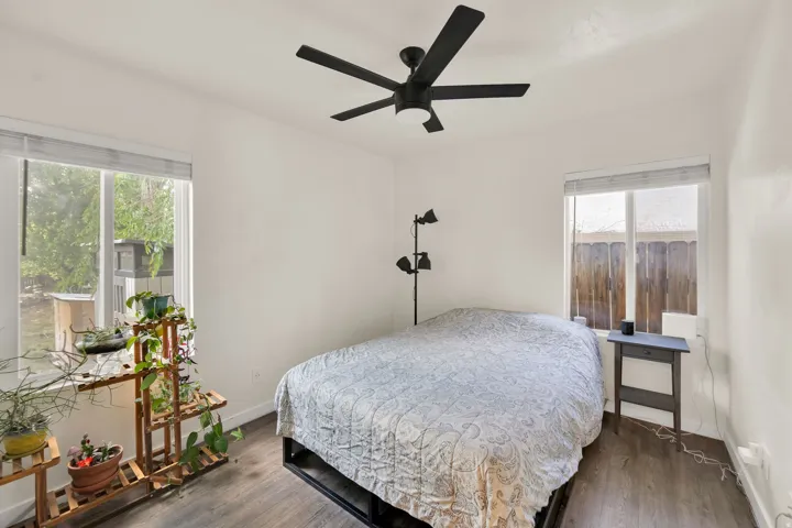 Bedroom featuring two windows, wood-finish flooring, and a modern ceiling fan