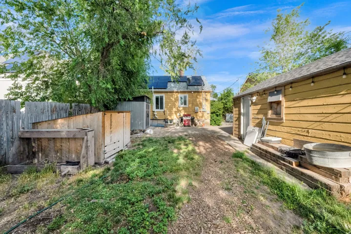 Fenced backyard featuring a gravel path and two accessory structures
