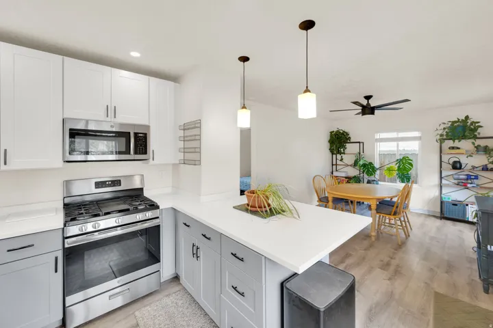 Open-concept kitchen featuring two-tone cabinetry, stainless steel appliances, and a peninsula with countertop seating