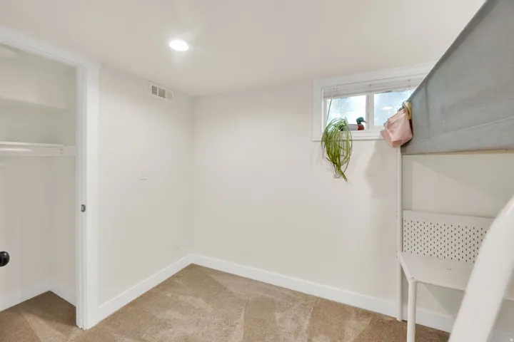 Carpeted room featuring a single window, white baseboards, and a built-in closet with shelving and a hanging rod