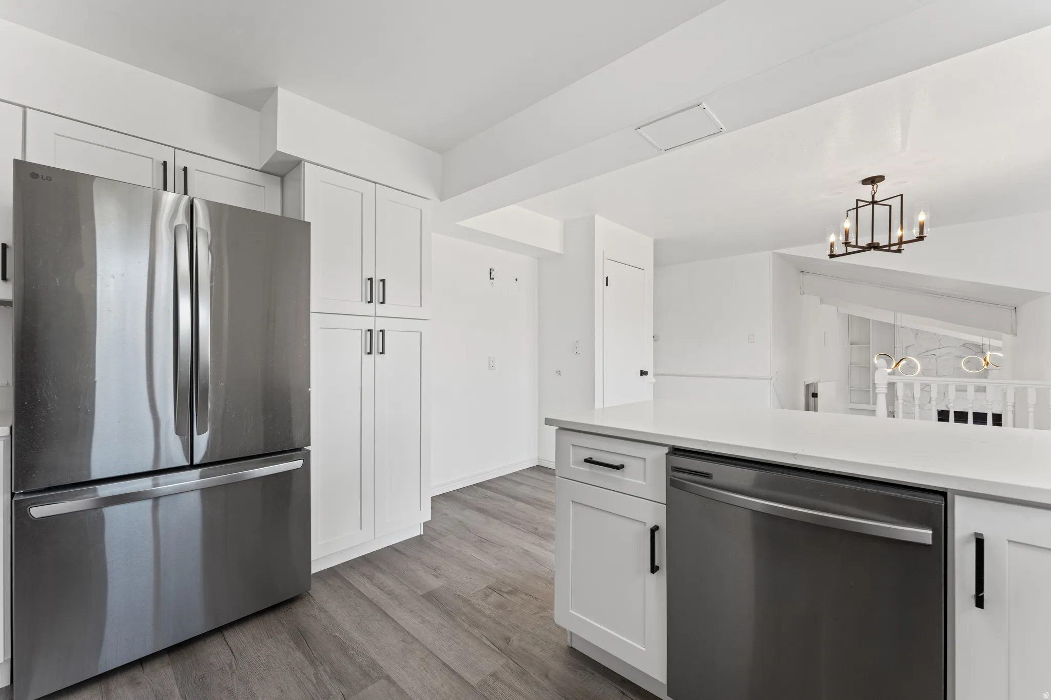 Kitchen featuring white shaker cabinetry, stainless steel appliances, white countertops, and wood-finish flooring