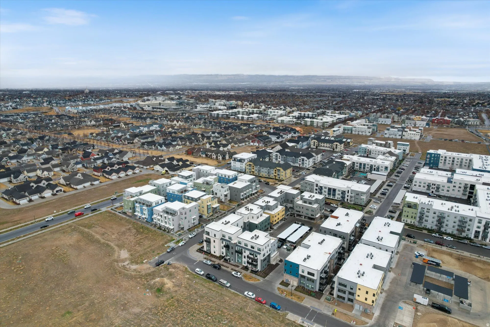 Aerial perspective showcasing a developing community with a mix of modern multi-story residential buildings and traditional single-family homes