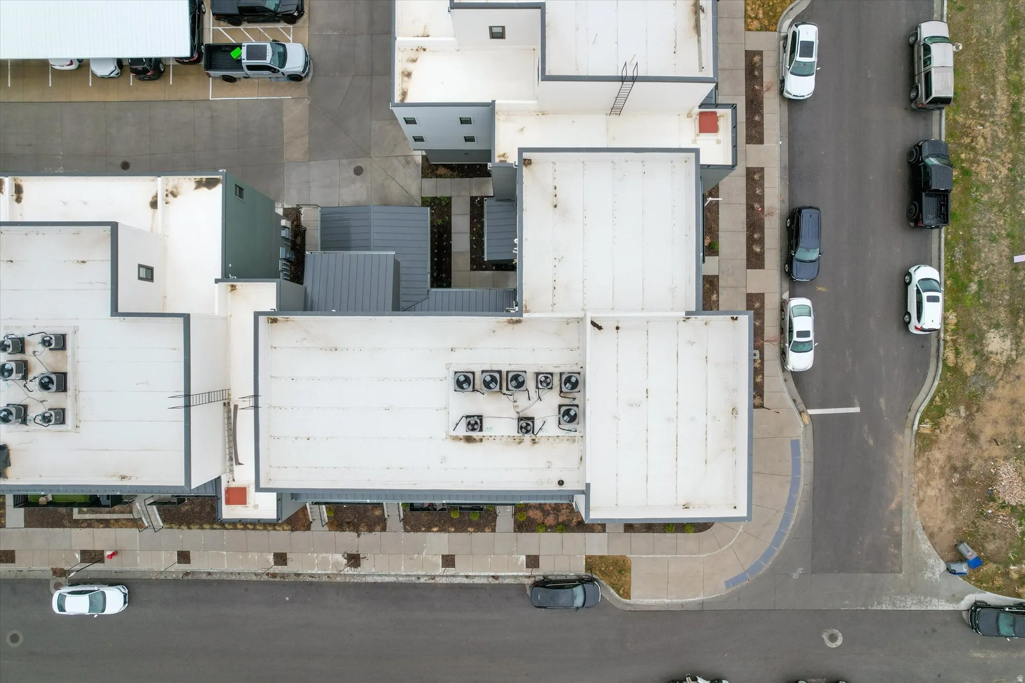Modern commercial building with a flat roof design, multiple rooftop HVAC units, and pedestrian walkways