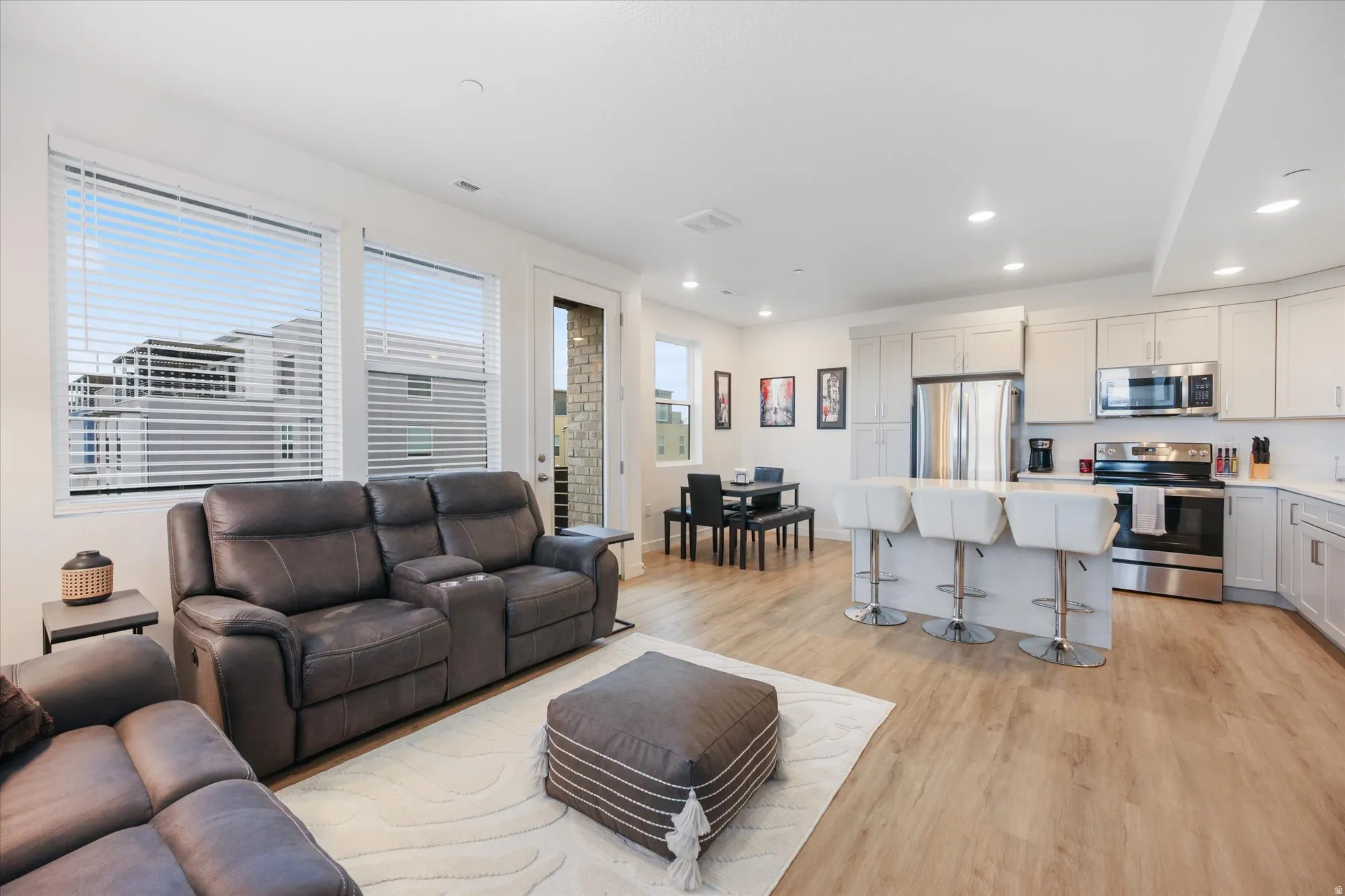 Open-concept living space featuring wood-finish flooring, recessed lighting, and large windows
