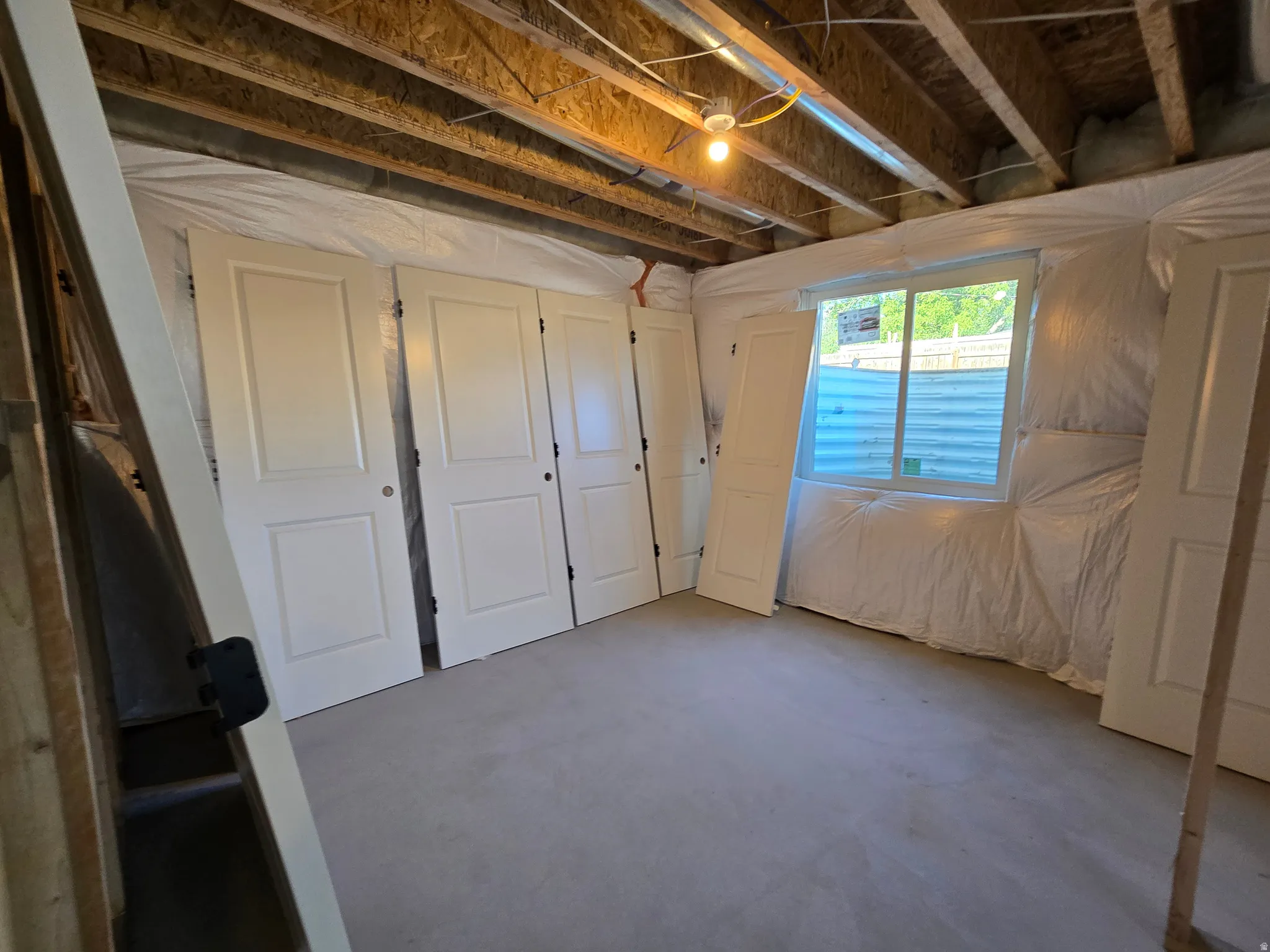 Unfinished basement space featuring exposed ceiling joists, a single window, and concrete flooring