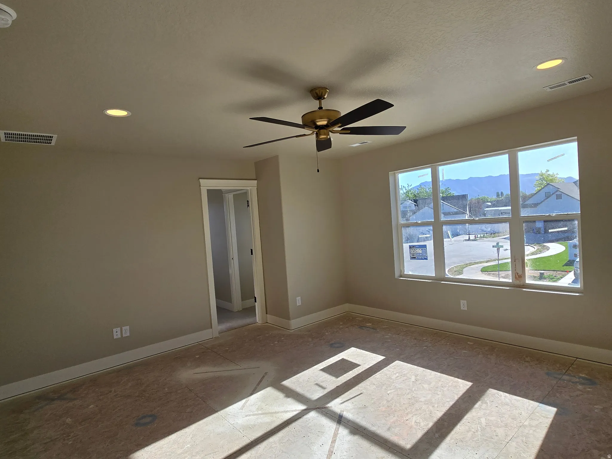 Spacious room featuring multiple recessed ceiling lights, a bronze and black ceiling fan, and a large multi-pane window