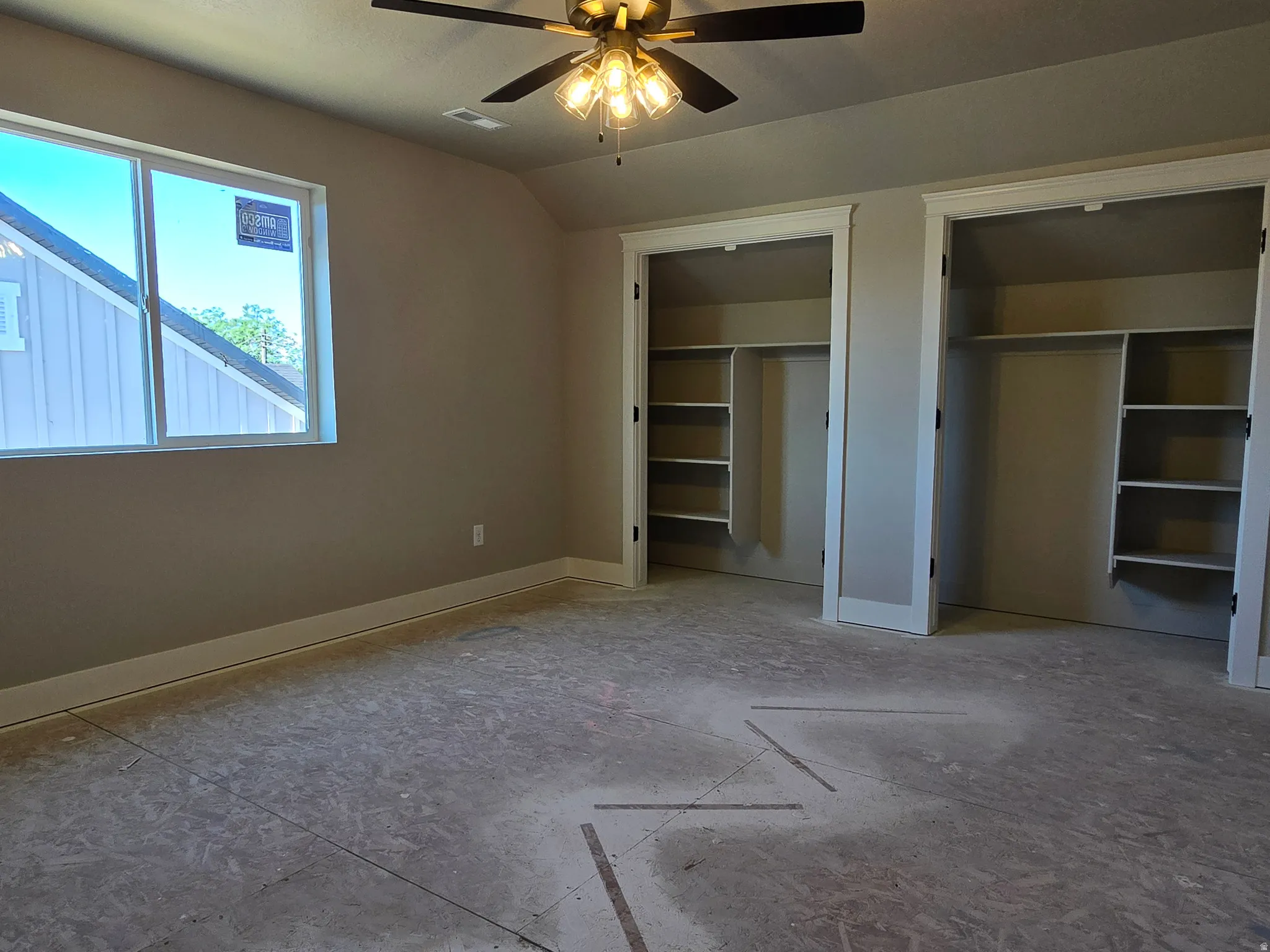 Bedroom featuring two closet spaces with built-in shelving, a large window, and a ceiling fan with integrated lighting