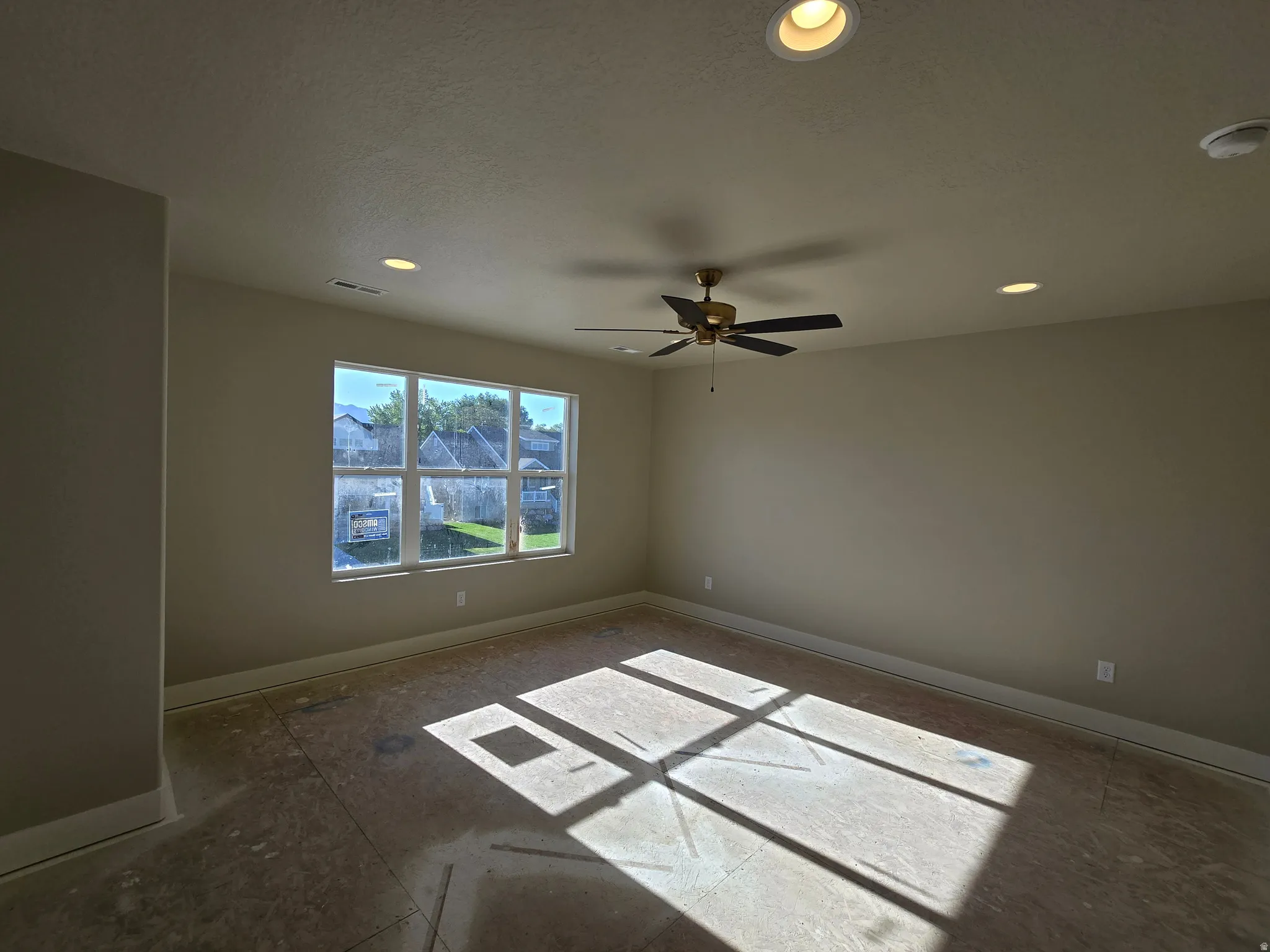 Spacious room with a large multi-pane window, recessed lighting, and a ceiling fan