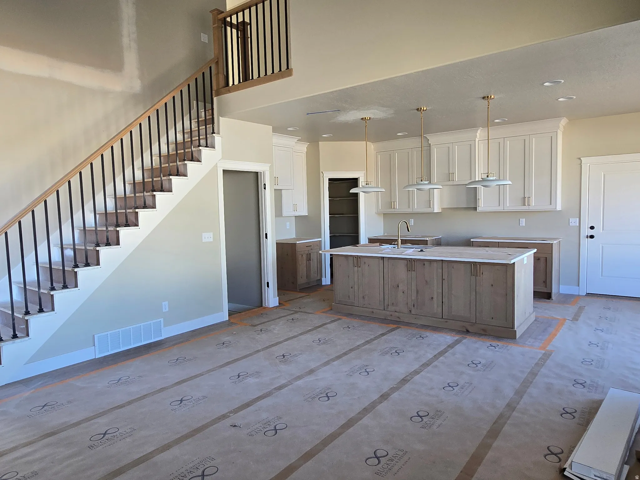 Open-concept kitchen and living area featuring a central island with wood-finish cabinetry, a large sink, and three pendant lights